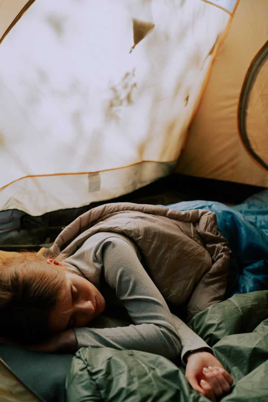 photo of a child sleeping in a tent. essential gear for fall camping with kids.